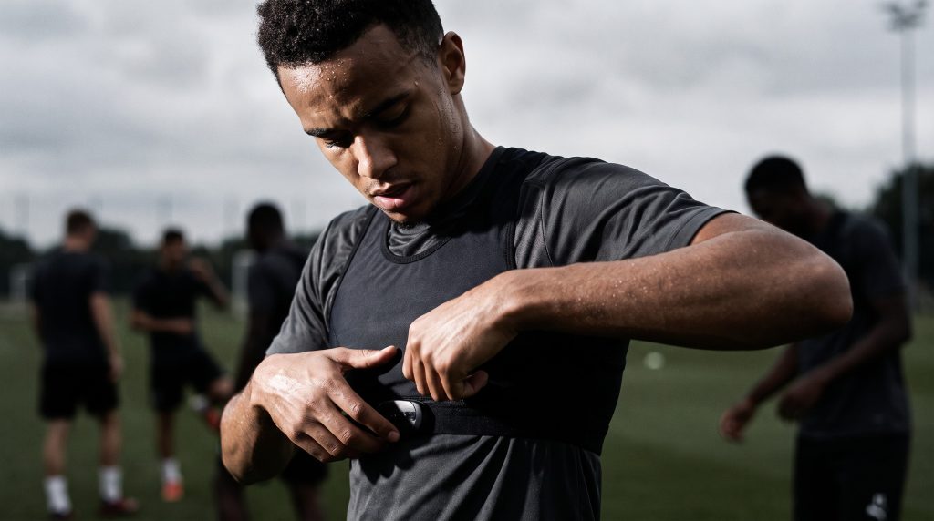 Polar H10 vs Garmin HRM-Pro Plus for Soccer: Which Chest Strap Should You Buy? 4 Soccer player adjusting a chest strap heart rate monitor on the touchline before training